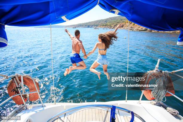 vue arrière du couple sauter dans l’eau - jumping of boat photos et images de collection