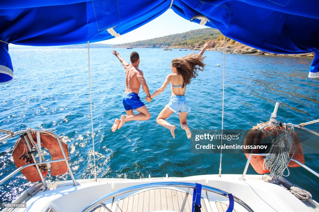 Rear view of couple jumping into ater