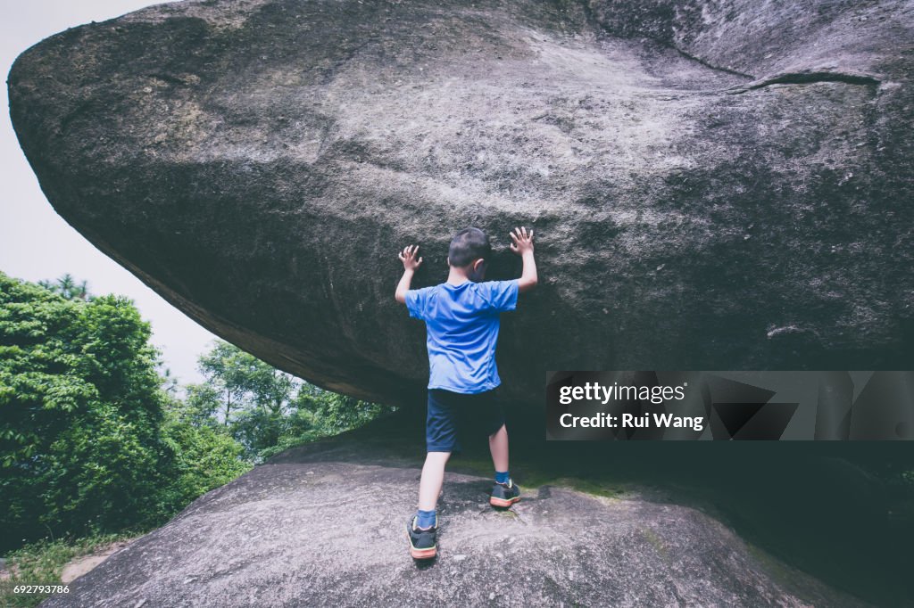 Silly boy pushing giant stone