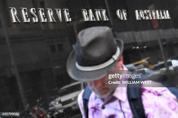 Man walks past the Reserve Bank of Australia sign in Sydney on June 6, 2017. - Australia's central bank held interest rates at a record low 1.50...