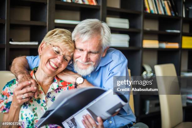 happy senior embracing couple reading a magazine in coffee bar, europe - magazine retreat day 2 stock pictures, royalty-free photos & images