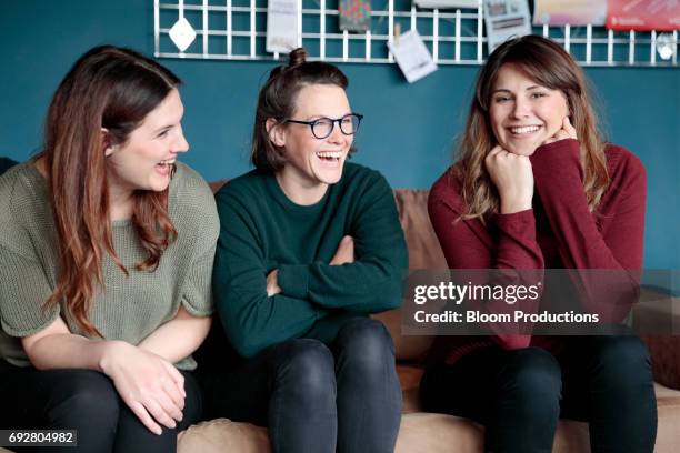 young women laughing together - group on couch stock-fotos und bilder