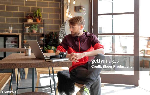 young man using a laptop - pantaloni di tuta foto e immagini stock