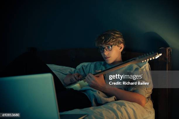 teenage boy playing guitar in front of computer - musical instrument stock pictures, royalty-free photos & images