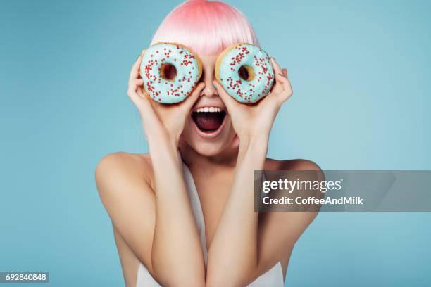 hübsche blondine mit bunten donuts - krapfen und doughnuts stock-fotos und bilder