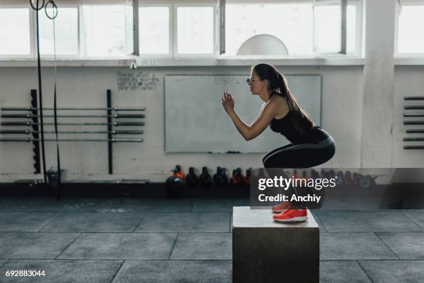 beautiful woman doing box squats at the gym - crouching stock pictures, royalty-free photos & images