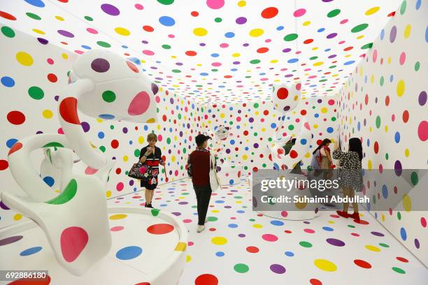 Visitors stand inside Japanese artist, Yayoi Kusama metal, fibreglass, urethane, paint, stickers installation titled 'With All My Love for Tulips, I...