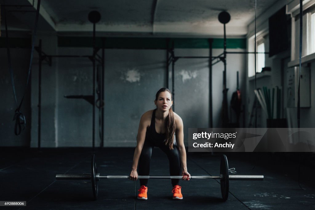 Determined young woman doing deadlift in the gym