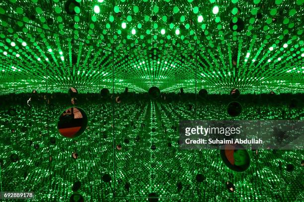 Visitor peeks through Japanese artist, Yayoi Kusama mirrored box and light bulbs installation, titled 'I Want to Love on the Festival Night 2017'...