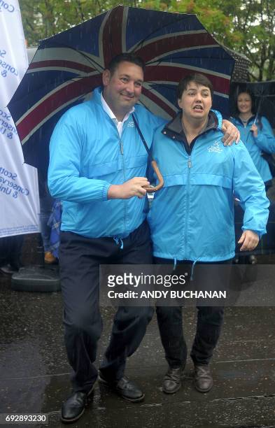 Scottish Conservative leader, Ruth Davidson and Edinburgh South West constituency candidate, Miles Briggs huddle under an umbrella in the rain as...