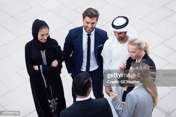 colleagues outside of their office having a conversation - united arab emirates business stock pictures, royalty-free photos & images