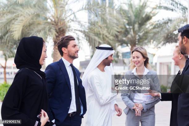 foreign businesspeople working with an emirati businessman in the middle east - bahrain man stock pictures, royalty-free photos & images