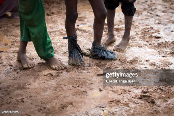 Baidoa, Somalia Hilac refugee camp. Children stand barefooted in the mud. One person has pulled plastic bags over his feet on May 01, 2017 in Baidoa,...