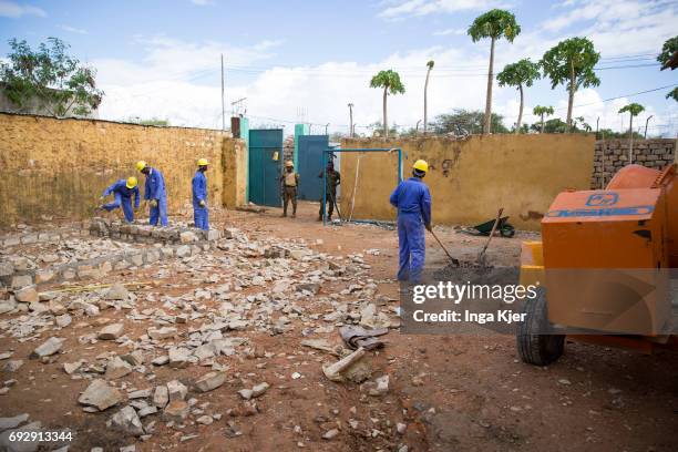 Baidoa, Somalia African men are building a wall in the rehabilitation center for former fighters of the Al-Shabaab militia. There are two guards at...