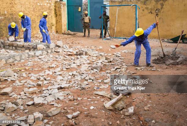 Baidoa, Somalia African men are building a wall in the rehabilitation center for former fighters of the Al-Shabaab militia. There are two guards at...