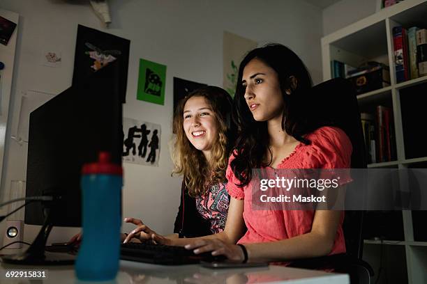 happy teenage girl using computer with friend in darkroom at home - arabic keyboard fotografías e imágenes de stock