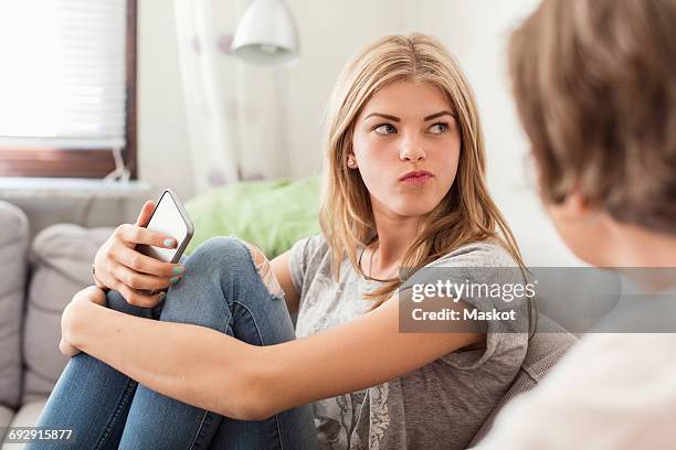 teenage girl making faces while sitting with mother on sofa at home - teen daughter stock pictures, royalty-free photos & images