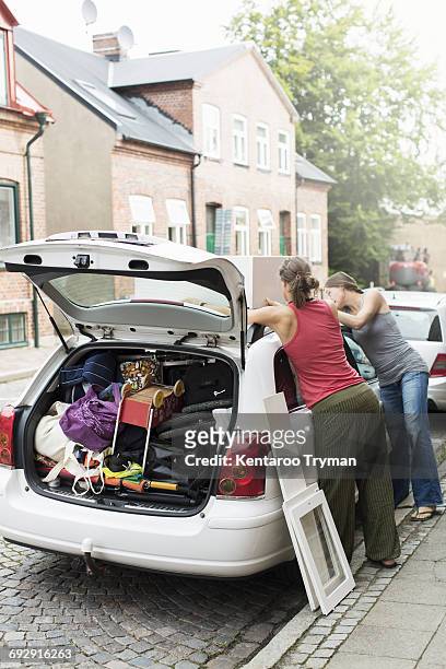 women loading luggage on car roof - stuffing photos et images de collection