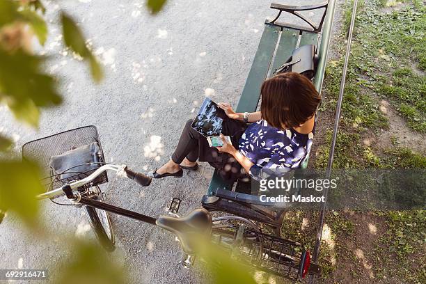 high angle view of businesswoman using digital tablet on park bench - bike headset stock-fotos und bilder