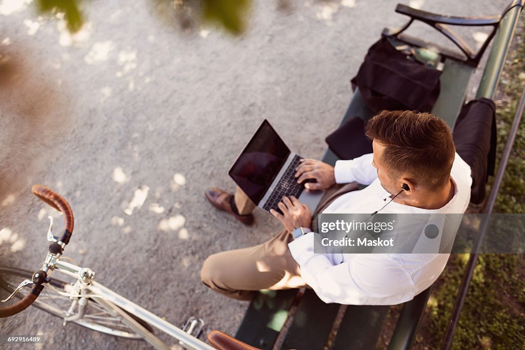 High angle view of businessman using laptop while sitting on park bench