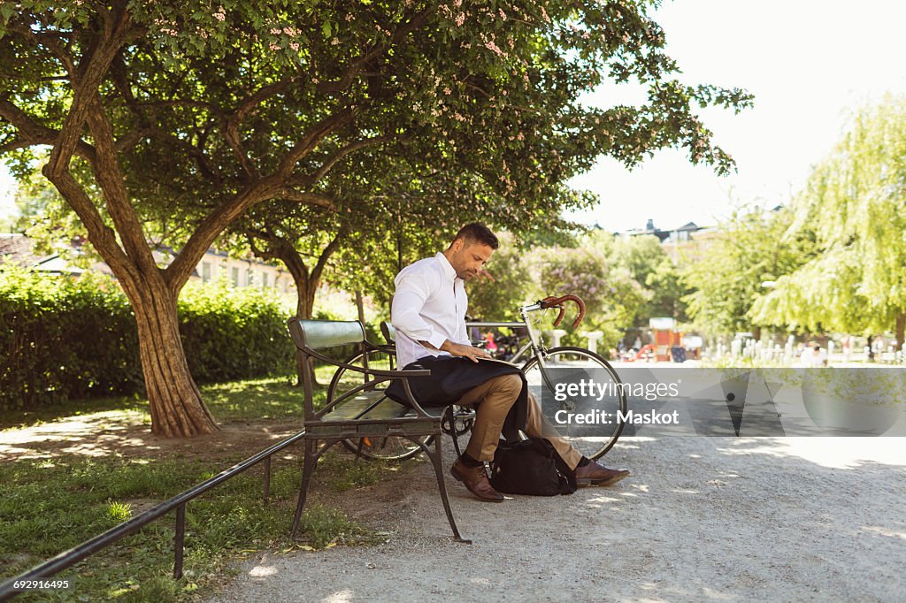 Businessman using laptop while sitting on bench at park