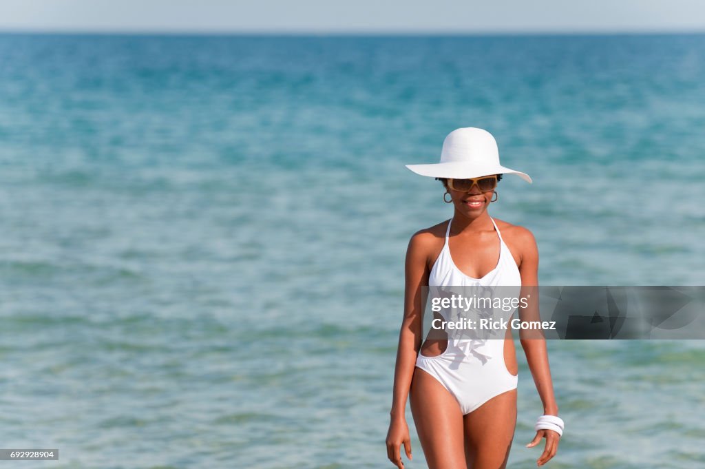Dark,mixed race woman in one piece swimsuit walking on the beach.