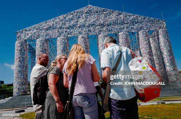 People pause in front of the "Parthenon of Books" by Argentinian artist Marta Minujin, at the Documenta 14 art exhibition in Kassel on June 2, 2017....