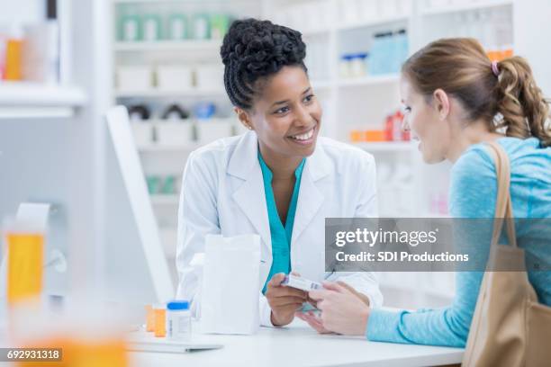 pharmacy customer asks pharmacist question about medication - pharmacy imagens e fotografias de stock