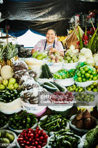 Laughing female vendor preparing produce at stand in marketplace