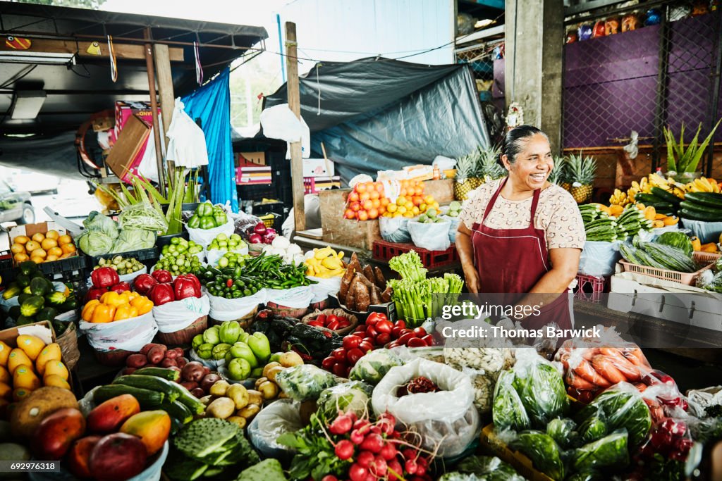 Laughing female produce vendor working at stand in marketplace