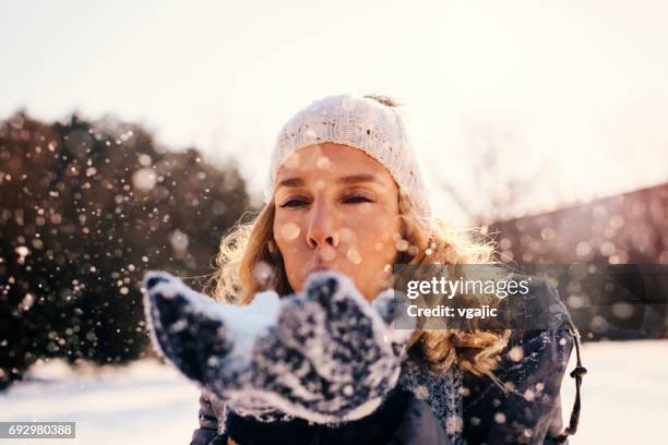 mitte erwachsene frau im freien im winter - schnee pusten stock-fotos und bilder