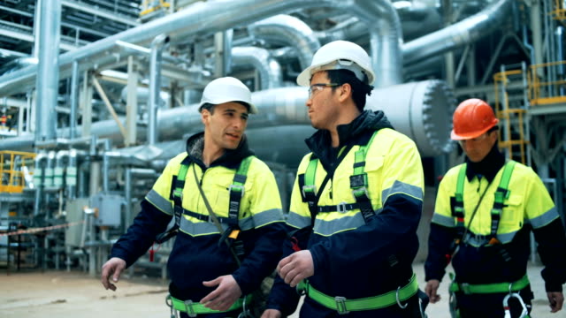 Team of workers walking on fuel plant