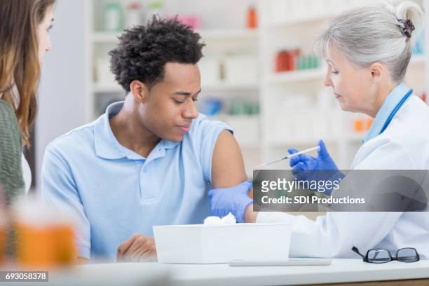 african american man receives flu vaccine - pharmacy vaccination stock pictures, royalty-free photos & images
