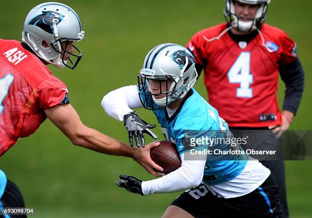 Carolina Panthers rookie running back Christian McCaffrey takes a handoff from quarterback David Ash, left, during the second session of the...