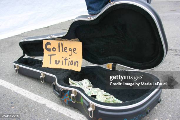 guitar case open with money for tips with "college tuition" sign - college tuition stock-fotos und bilder