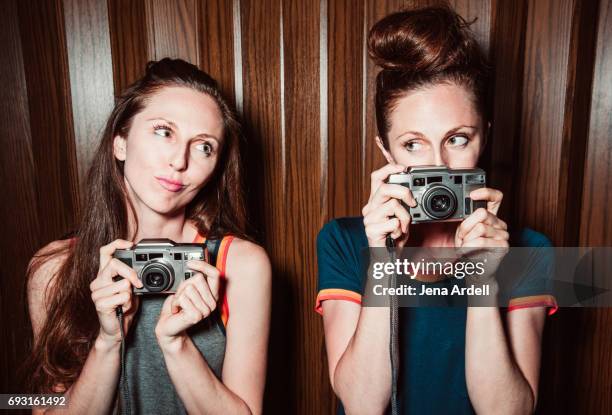 twins women holding cameras - zwilling stock-fotos und bilder