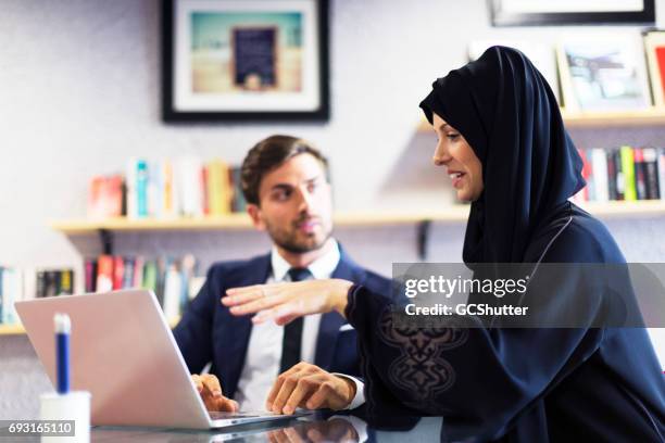 arabische geschäftsfrau mit ihrem kollegen arbeiten - emirati guy using laptop stock-fotos und bilder