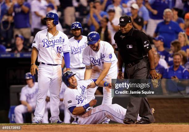 Alex Gordon of the Kansas City Royals is helped up by Mike Moustakas after stumbling over home plate as he scores on a three RBI double by Whit...