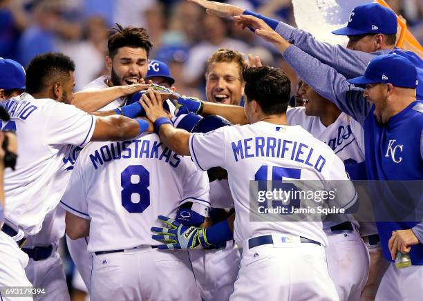 Mike Moustakas of the Kansas City Royals is congratulated by teammates at home plate after hitting a walk-off game-winning home run during the 9th...