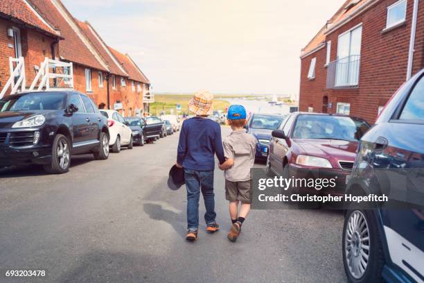 young brothers walking down quiet road - blakeney stock pictures, royalty-free photos & images