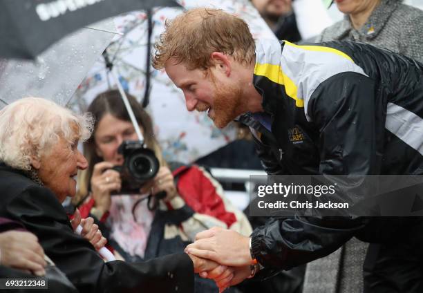 Patron of the Invictus Games Foundation Prince Harry hugs 97 year old Daphne Dunne during a walkabout in the torrential rain ahead of a Sydney 2018...