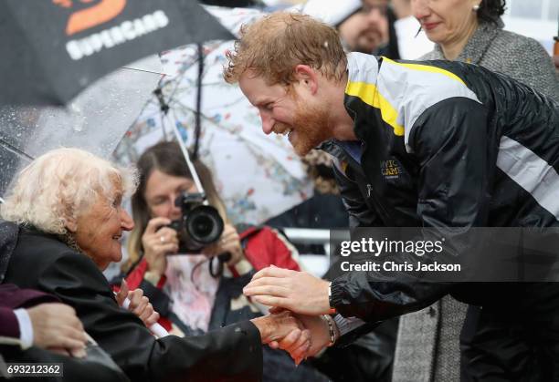 Patron of the Invictus Games Foundation Prince Harry hugs 97 year old Daphne Dunne during a walkabout in the torrential rain ahead of a Sydney 2018...