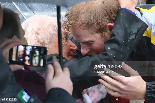 Britain's Prince Harry leans over to hug Daphne Dunne during an event where he met members of the public in Sydney on June 7, 2017. Prince Harry on...