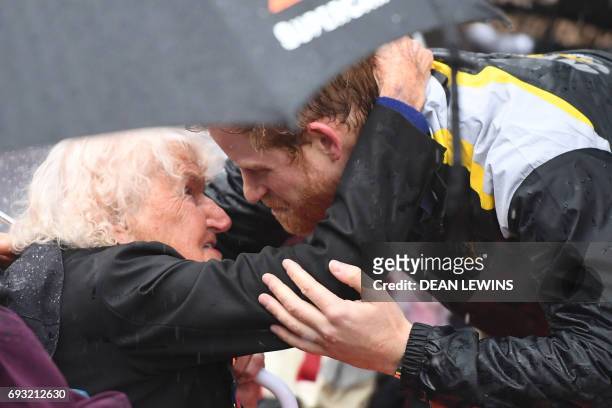 Britain's Prince Harry hugs Daphne Dunne during a walk around The Rocks in Sydney on June 7, 2017. Prince Harry on June 7 paid tribute to victims of...