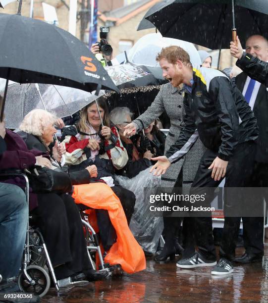 Patron of the Invictus Games Foundation Prince Harry hugs 97 year old Daphne Dunne during a walkabout in the torrential rain ahead of a Sydney 2018...