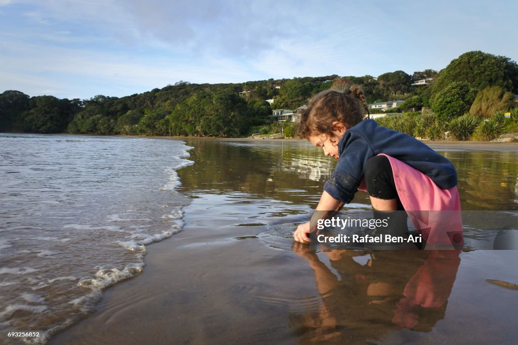 Small girl plays with sand on the beach