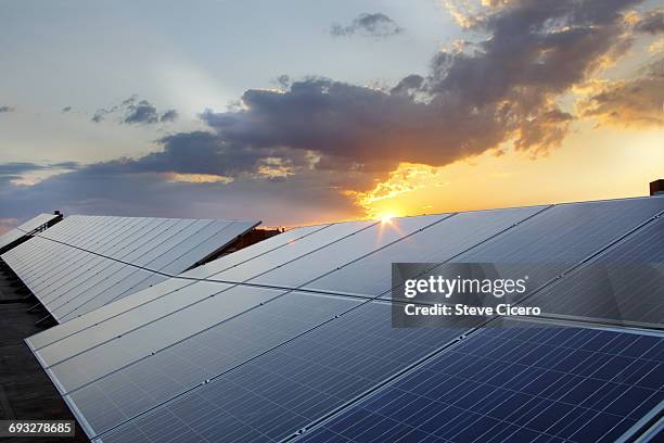 grouping of photovoltaic solar panels on rooftop - zonnepanelen stockfoto's en -beelden