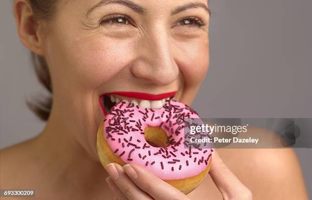 woman enjoying eating doughnut - transfettsäure stock-fotos und bilder