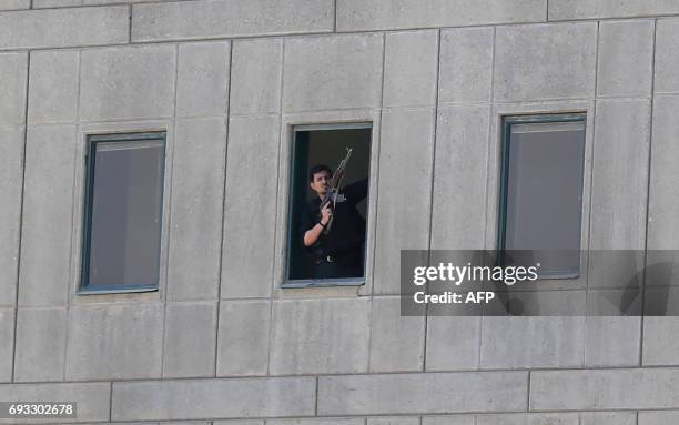 An Iranian policeman holds a weapon as he stands by a window at the Iranian parliament in the capital Tehran on June 7, 2017 during an attack on the...
