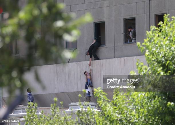 Police officer dangles a child from the window as the police conduct an operation against the attacker in the parliament building after gunmen opened...